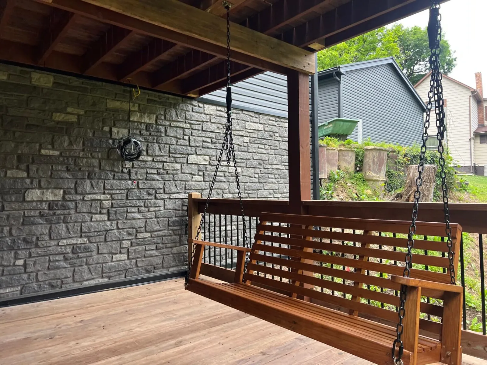 Covered deck with porch swing and stone wall